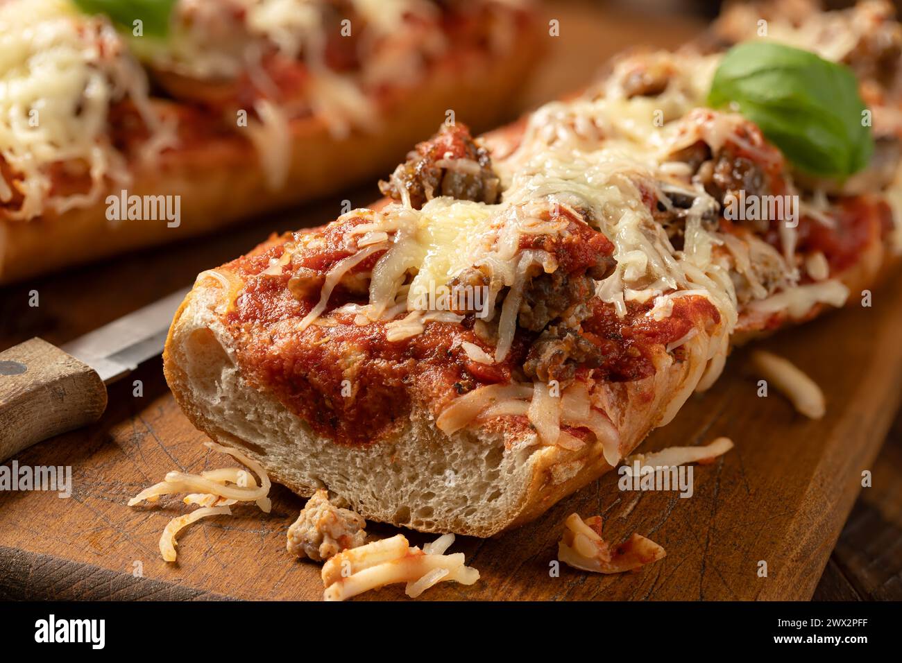 Primo piano di pane per pizza fatto con salsiccia, mozzarella e pomodoro su un vecchio tagliere di legno Foto Stock