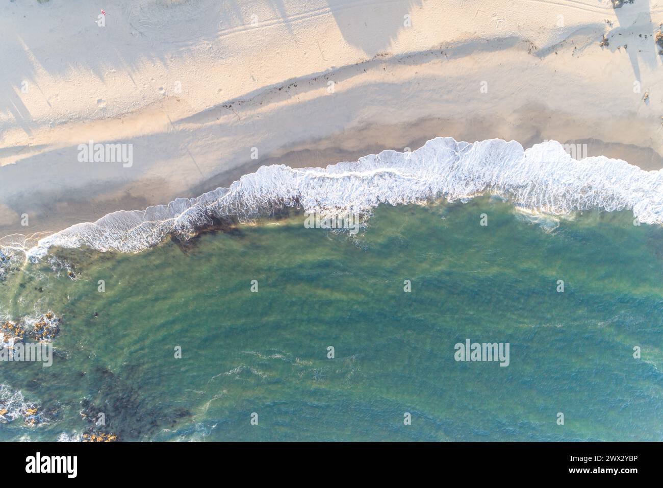 vista aerea aerea dall'alto delle onde che si infrangono sulla riva di una spiaggia all'alba, sullo sfondo estivo Foto Stock