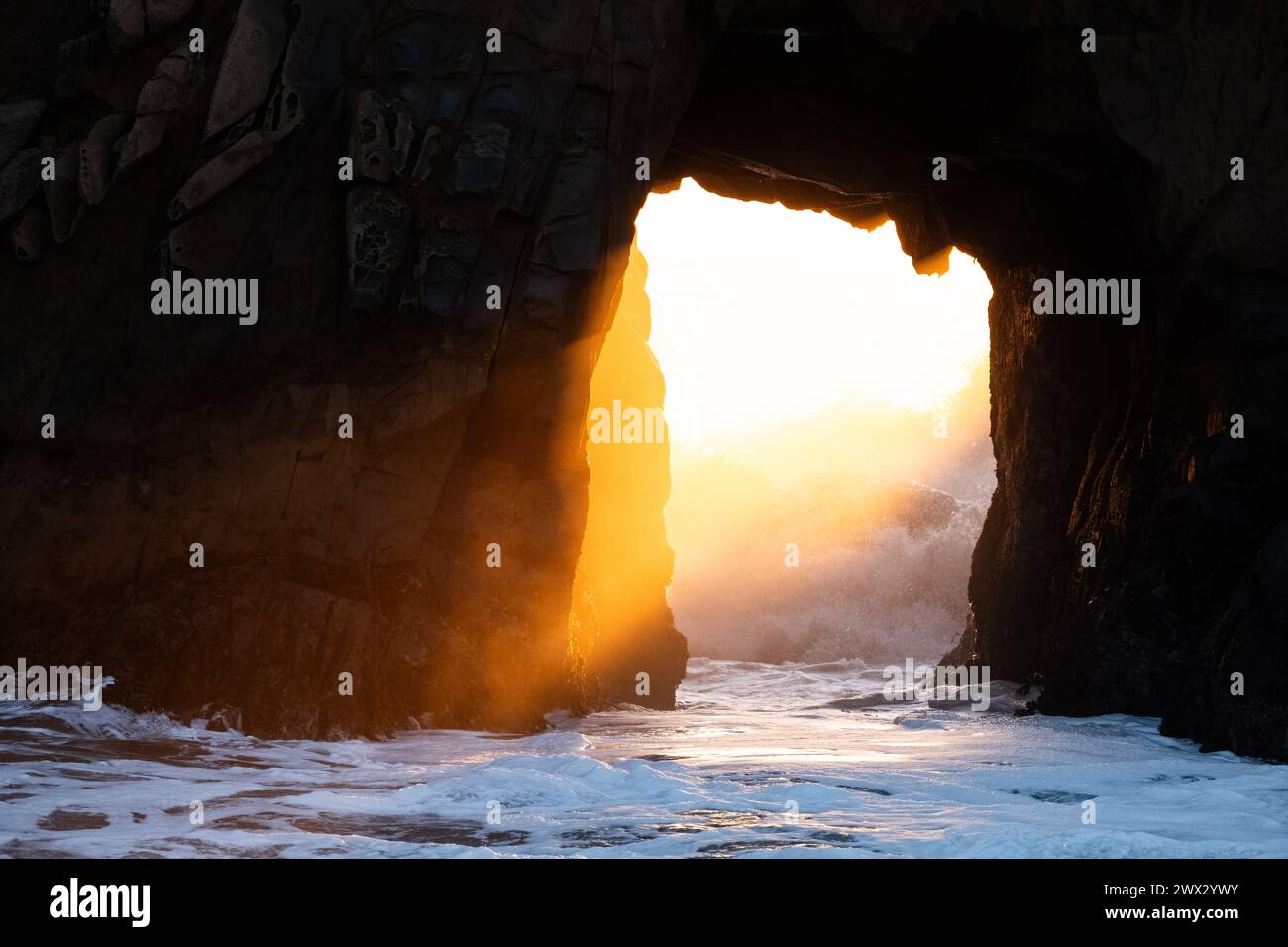 Sunset illumina la finestra nella roccia di Keyhole Arch a Pfeiffer Beach a Big Sur sull'Oceano Pacifico in California, USA. Foto Stock