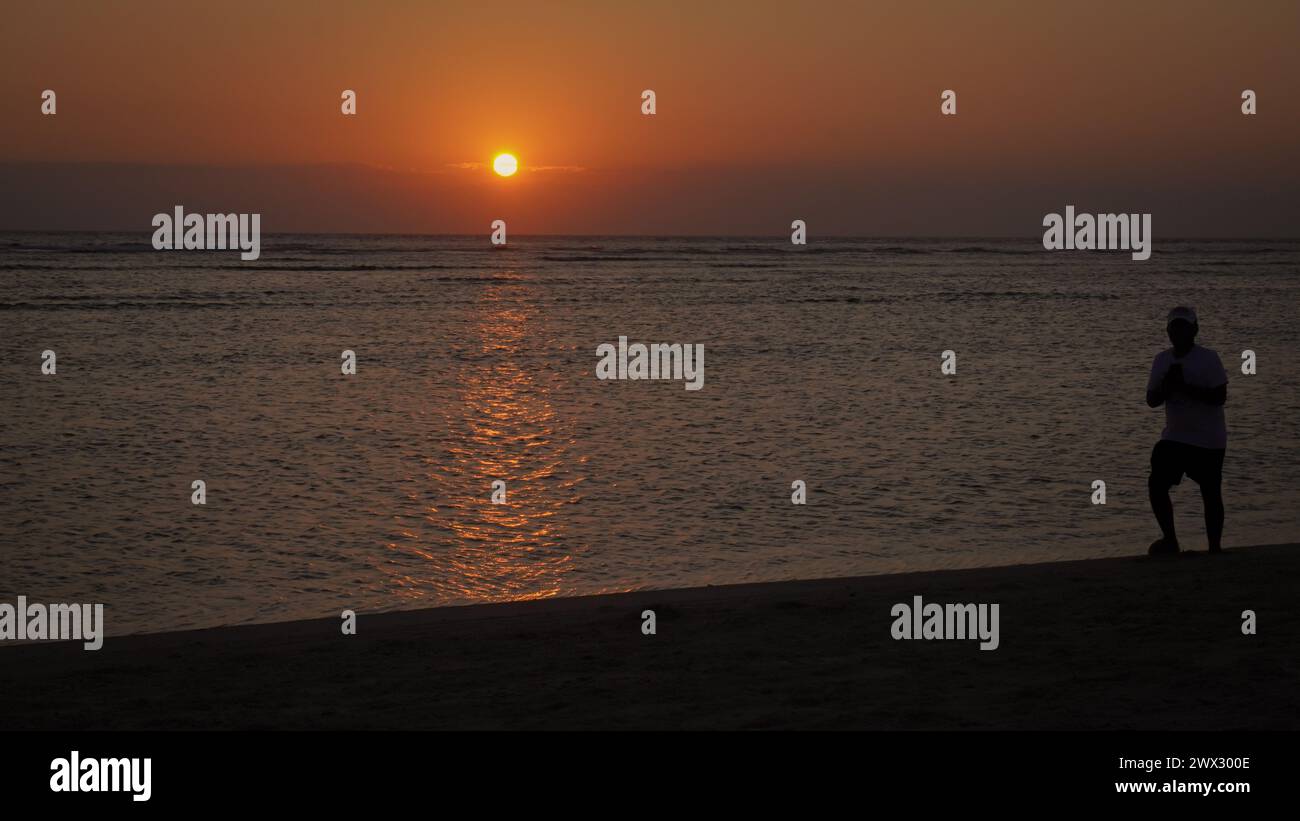 Sagome di persone che svolgono le loro attività al crepuscolo sulla spiaggia dell'isola di Gili Trawangan, Lombok Foto Stock