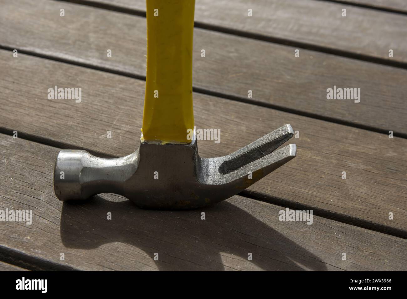 testa di un martello metallico poggiato su tavole di legno marrone scuro Foto Stock