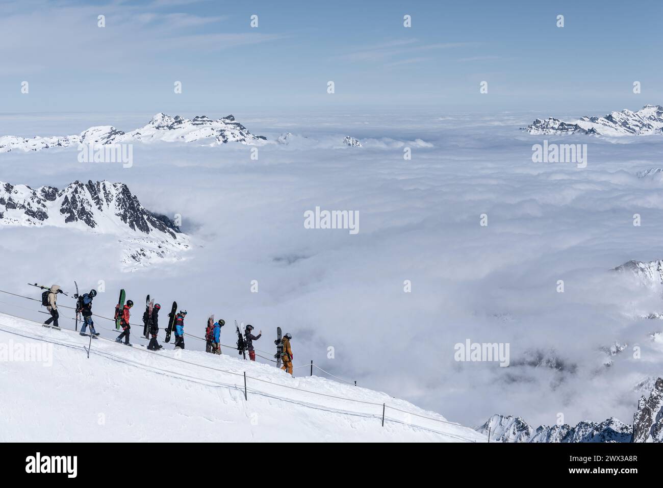 Chamonix, Francia - 4 marzo 2024: Un gruppo di 8 snowboarder e sciatori che camminano lungo la pista sulla cresta da Aiguille du Midi alla Vallee Blanche Foto Stock