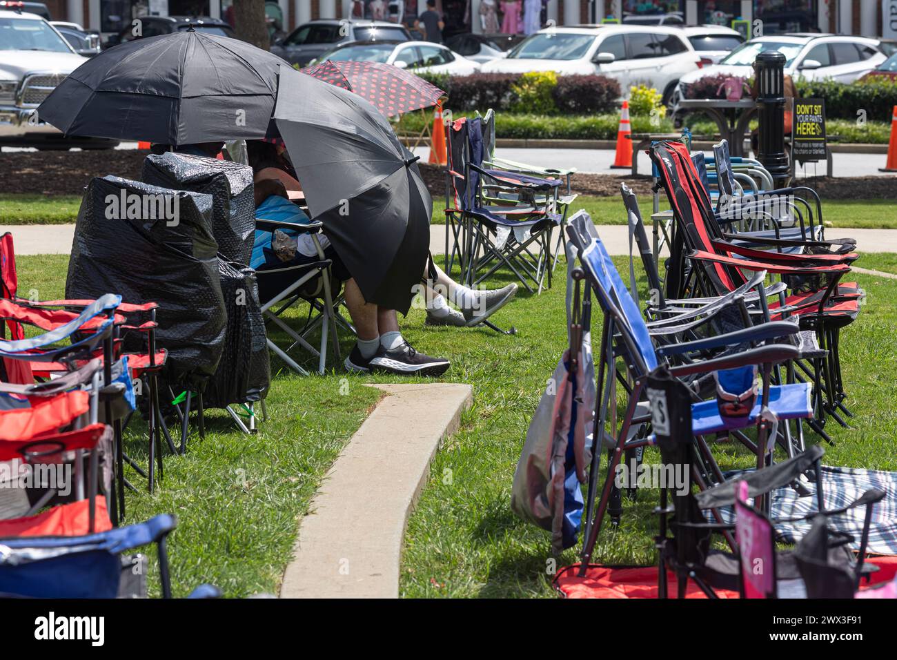 Suwanee, GA / USA - 12 agosto 2023: Due persone usano gli ombrelli per proteggere il caldo torrido in attesa dell'inizio di un concerto estivo. Foto Stock
