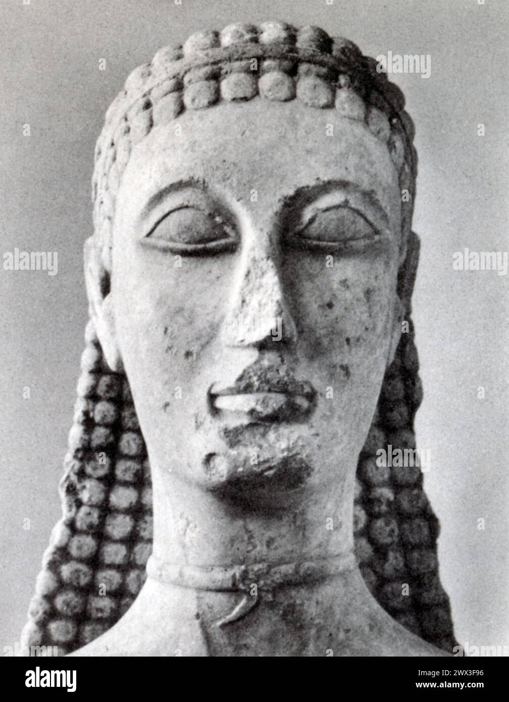 Questa fotografia raffigura la testa di un giovane, scolpita in marmo e originaria dell'Attica, Grecia, intorno al 600 a.C. questo periodo, conosciuto come l'era arcaica nella storia greca, è stato caratterizzato dallo sviluppo e dalla raffinatezza della scultura, segnando una transizione dalle forme più rigide del periodo geometrico alle rappresentazioni più naturalistiche viste nell'arte greca successiva. Foto Stock