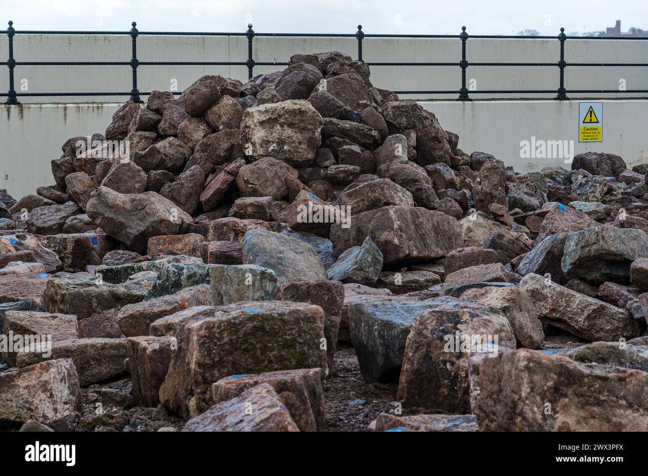 North Berwick, East Lothian, Scozia, Regno Unito, 27 marzo 2024. Riparazioni alle mura del porto: La North Berwick Harbour Trust sta raccogliendo fondi per riparazioni ai danni causati dalle tempeste invernali combinate con le alte maree primaverili. Sono in corso lavori e grandi mucchi di pietre, alcuni recuperati dalle mura vecchie di 200 anni, si trovano intorno all'area del porto. Crediti: Sally Anderson/Alamy Live News Foto Stock