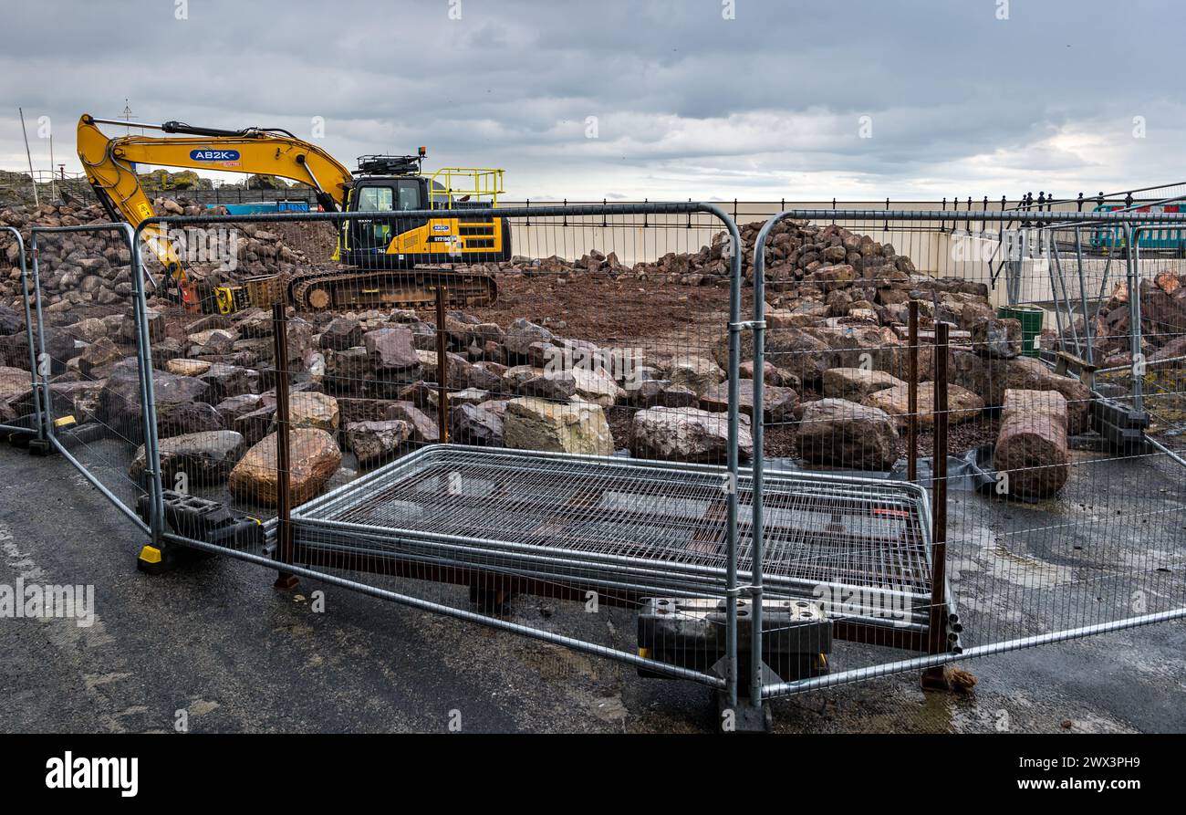 North Berwick, East Lothian, Scozia, Regno Unito, 27 marzo 2024. Riparazioni alle mura del porto: La North Berwick Harbour Trust sta raccogliendo fondi per riparazioni ai danni causati dalle tempeste invernali combinate con le alte maree primaverili. Sono in corso lavori e grandi mucchi di pietre, alcuni recuperati dalle mura vecchie di 200 anni, si trovano intorno all'area del porto. Crediti: Sally Anderson/Alamy Live News Foto Stock