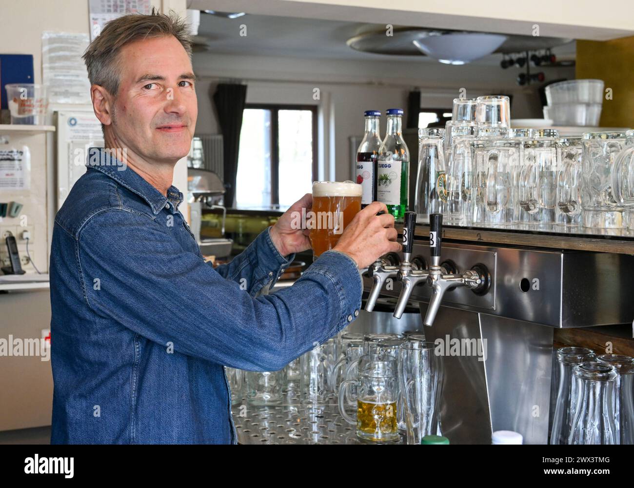 Berlino, Germania. 27 marzo 2024. Dominik Ries, proprietario dello Schleusenkrug, si serve della birra al bar della birreria all'aperto. Crediti: Jens Kalaene/dpa/Alamy Live News Foto Stock