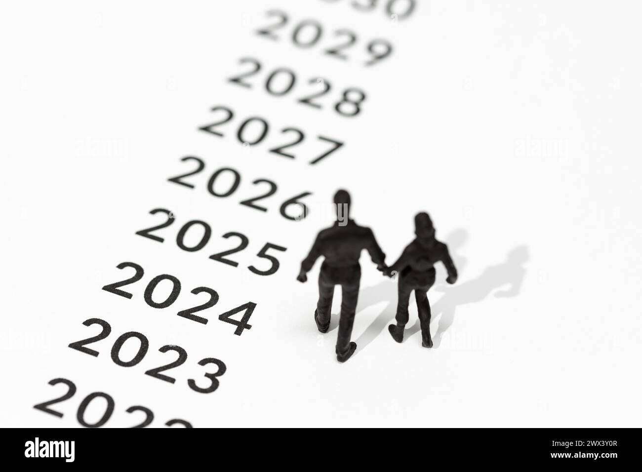 Uomini e donne coppie di figurine che guardano agli anni futuri segnati sul terreno. Concetto di piano familiare. Copia spazio Foto Stock