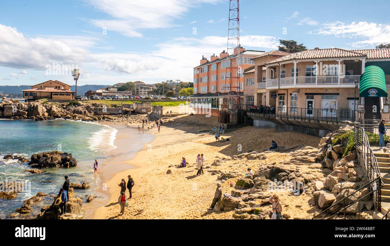 Macabee Beach o McAbee Beach vicino a Cannery Row a Monterey, California, Stati Uniti. Turisti in spiaggia con edifici storici sulla costa. Foto Stock