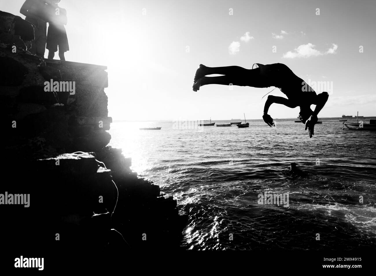 Salvador, Bahia, Brasile - 31 maggio 2019: Si vede un giovane, in silhouette, saltare in mare dal molo di Porto da barra nella città di Salvador, Foto Stock