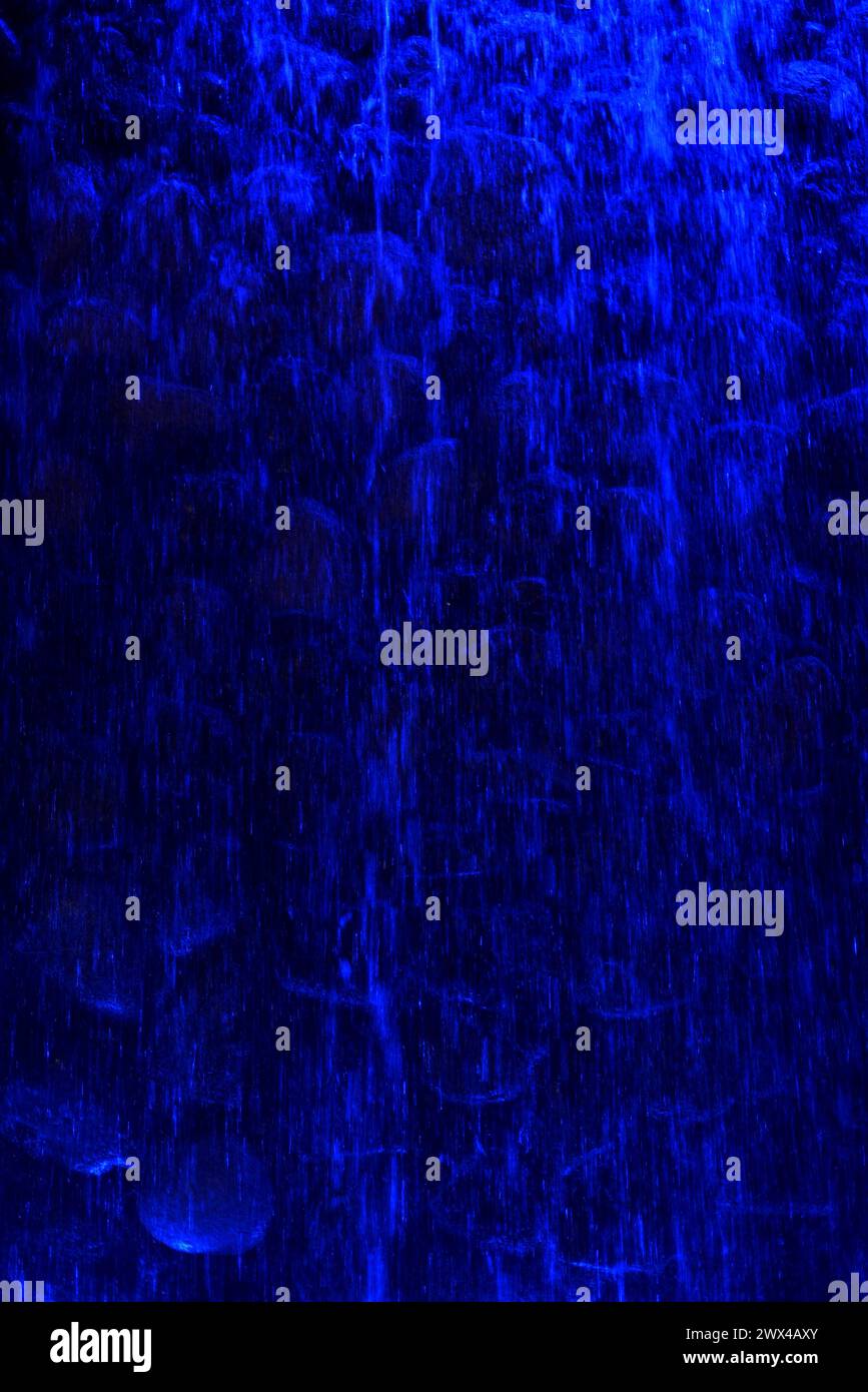 Immagine verticale di una cascata artificiale illuminata da luci blu Foto Stock