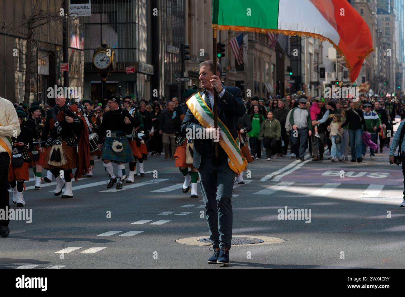 Un partecipante alla parata marcia mentre sventola la bandiera irlandese alla New York City St. Patrick's Day Parade sulla Fifth Avenue. La parata annuale che commemora la cultura irlandese attira agenti di polizia, vigili del fuoco, politici, bande e rivelatori nel centro di Manhattan, New York. Foto Stock