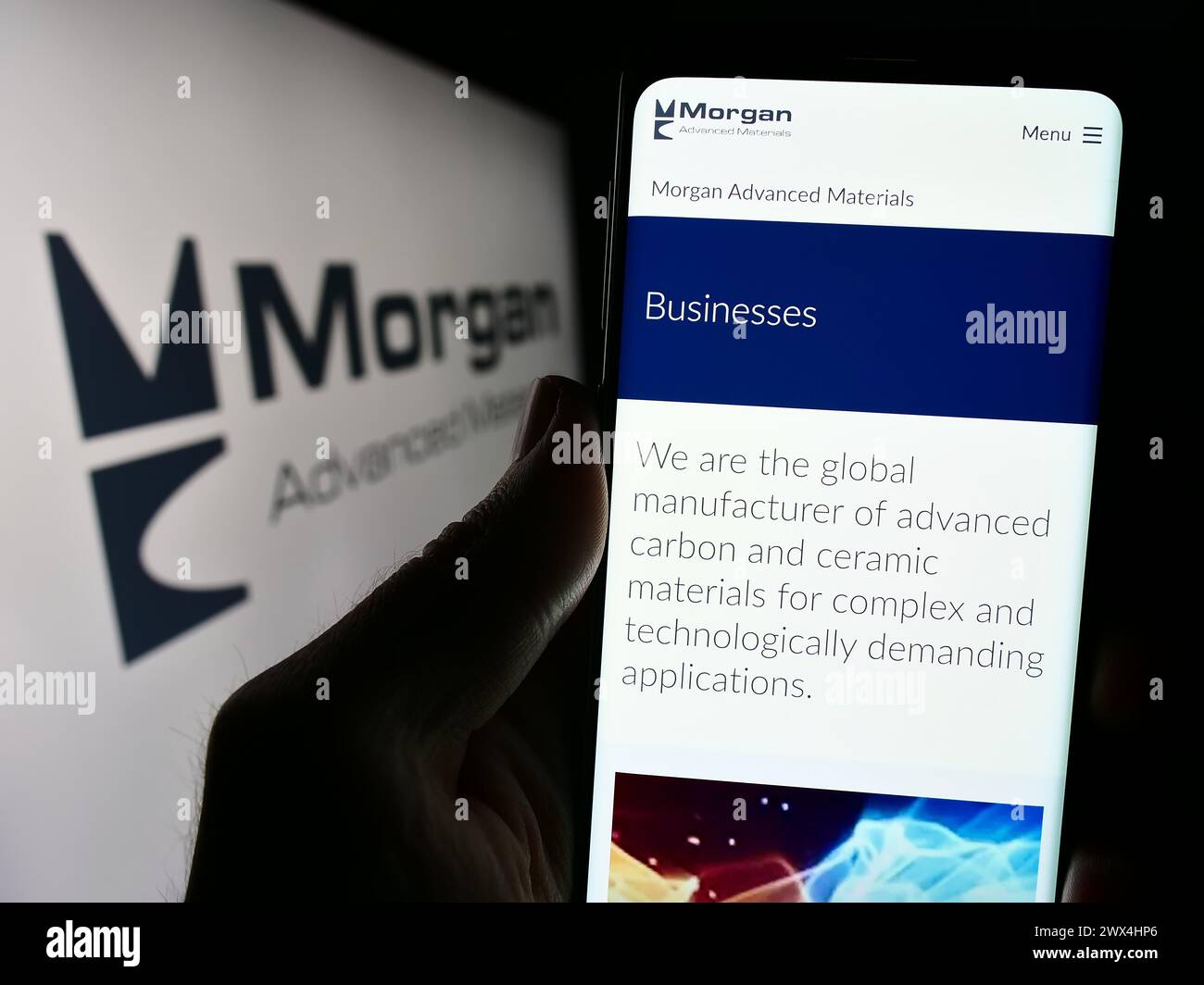 Persona che detiene un cellulare con la pagina web della società britannica Morgan Advanced Materials plc davanti al logo. Messa a fuoco al centro del display del telefono. Foto Stock