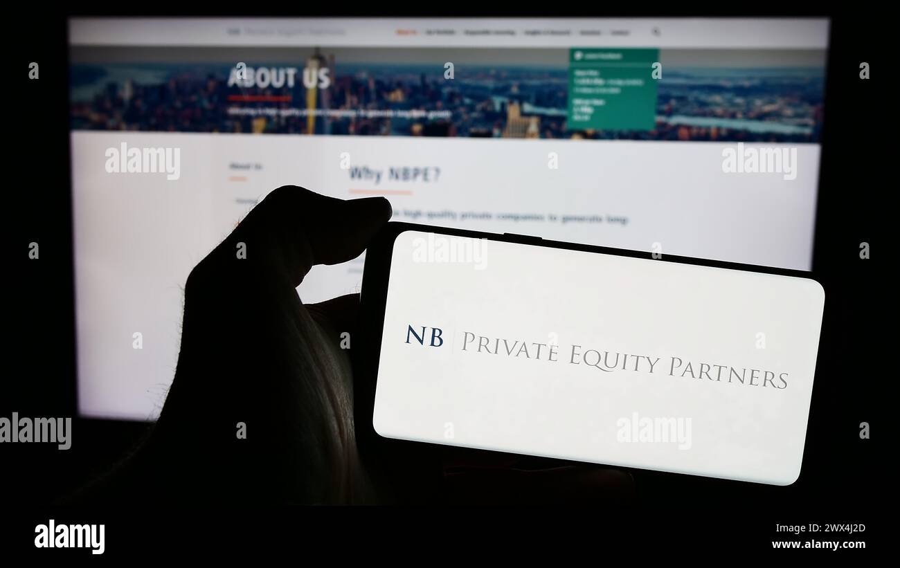 Persona che detiene lo smartphone con il logo della società britannica NB Private Equity Partners Ltd. (NBPE) di fronte al sito web. Mettere a fuoco il display del telefono. Foto Stock