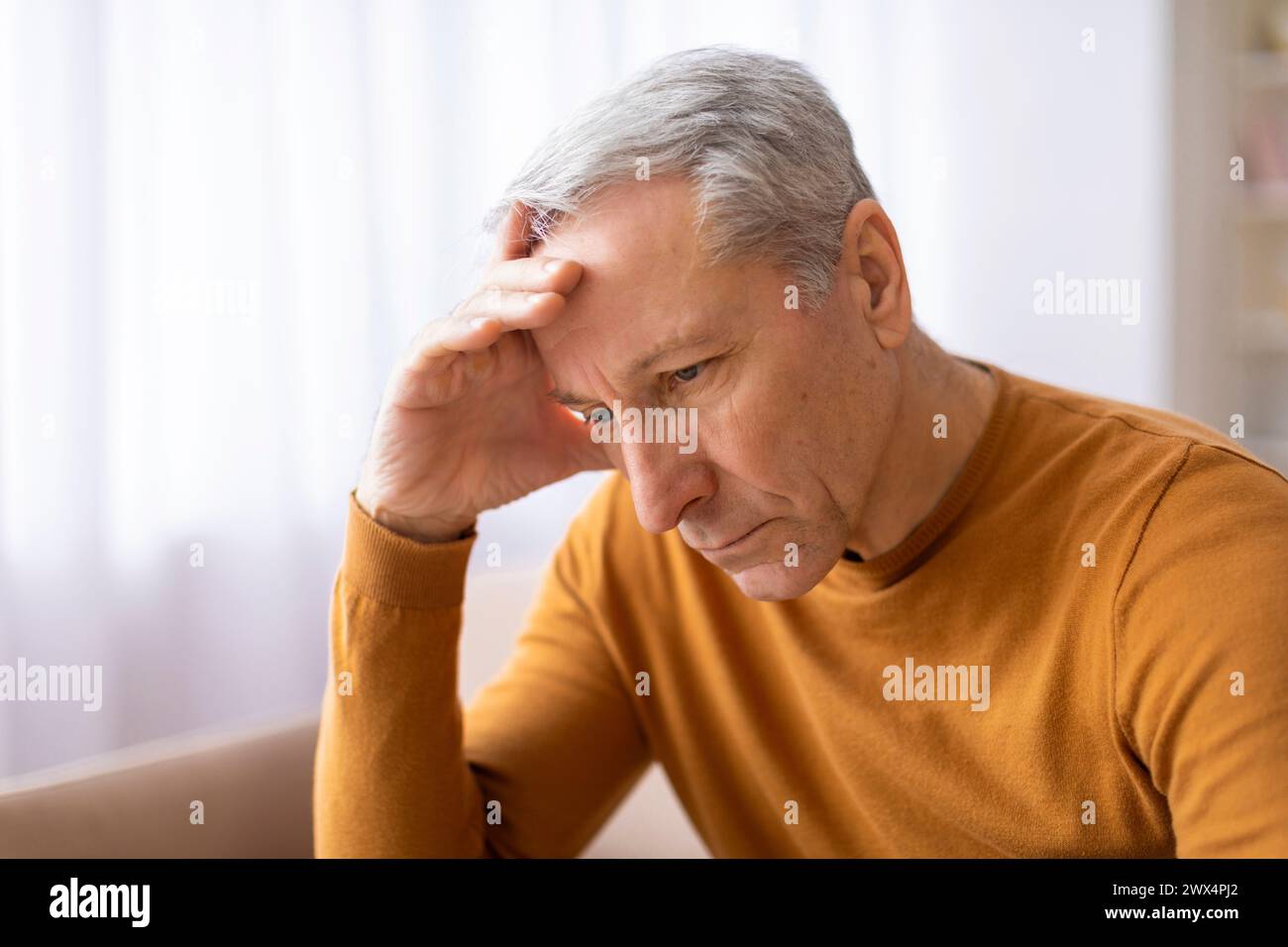 Un uomo anziano tiene la fronte in modo sconvolto Foto Stock