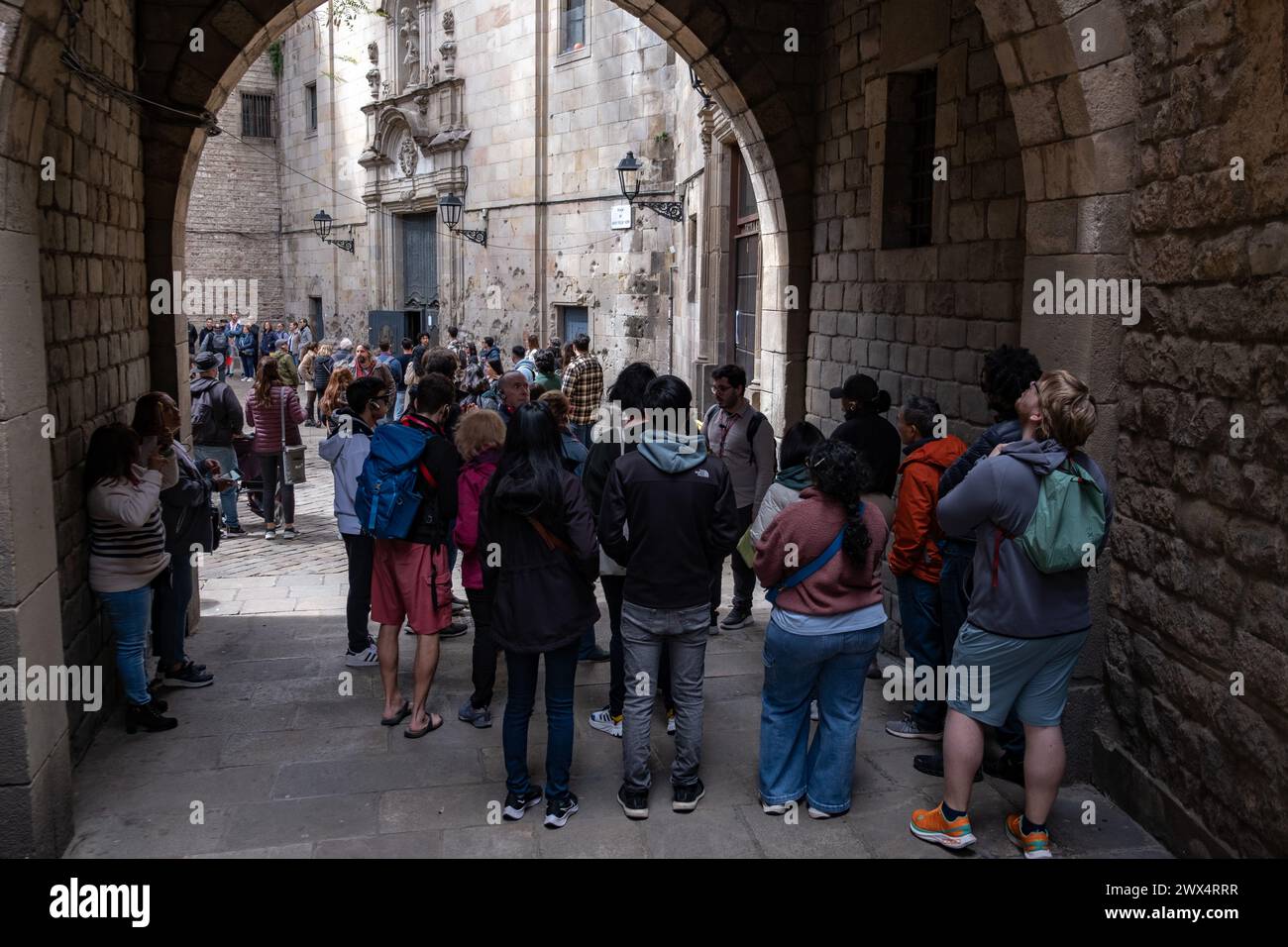 Diversi gruppi di visitatori nazionali e turisti sono visti partecipare a visite culturali nella Plaza de Sant Felip Nerí, nel cuore del quartiere gotico di Barcellona. Barcellona ha un tasso di occupazione alberghiera di oltre il 80% previsto per le vacanze di Pasqua. Per i residenti, l'aumento di visitatori e turisti nelle strade e nelle piazze che visitano il patrimonio architettonico della città durante la settimana Santa è già evidente. Foto Stock