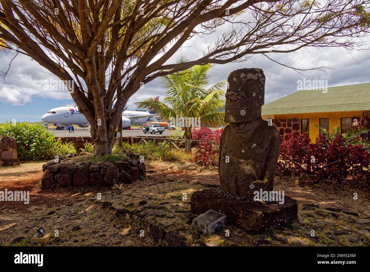 Isola di Pasqua, Cile. 31 dicembre 2023. Un aereo Latam sull'asfalto dell'aeroporto internazionale di Mataveri dietro un moai scolpito da Manuel Tuki. Foto Stock