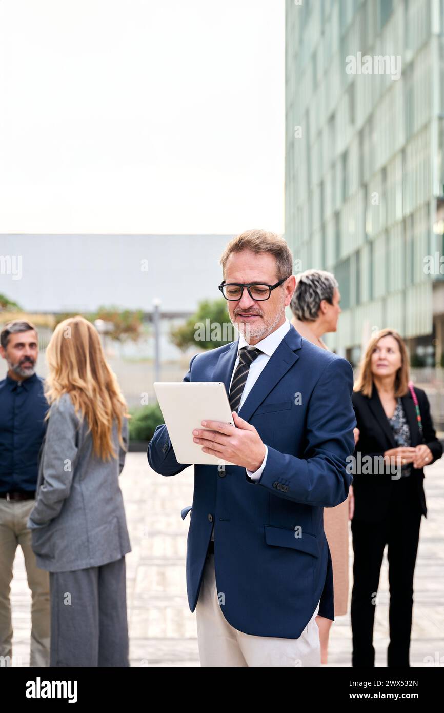 Un uomo caucasico di mezza età che lavora in abbigliamento formale, in piedi di fronte a una folla Foto Stock