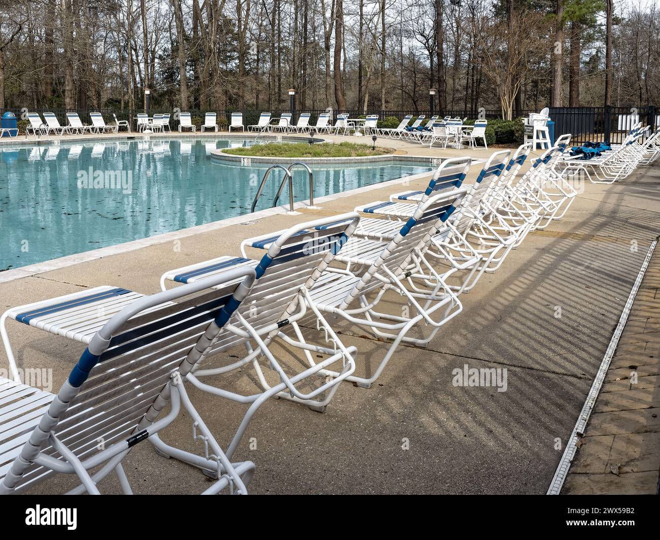 Terrazza con piscina con sedie a sdraio allineate in attesa di folle estive presso una grande piscina in una comunità residenziale a Pike Road Alabama, Stati Uniti. Foto Stock