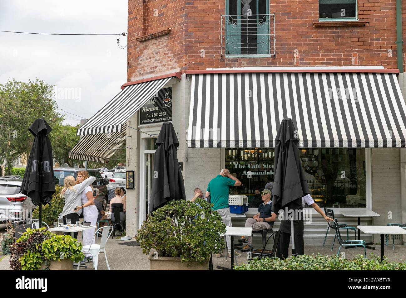 Annandale sobborgo nell'entroterra ovest di Sydney, Cafe Sienna con gente che mangia fuori, giovani ragazze abbracciano addio, Sydney, NSW, Australia, 2024 Foto Stock