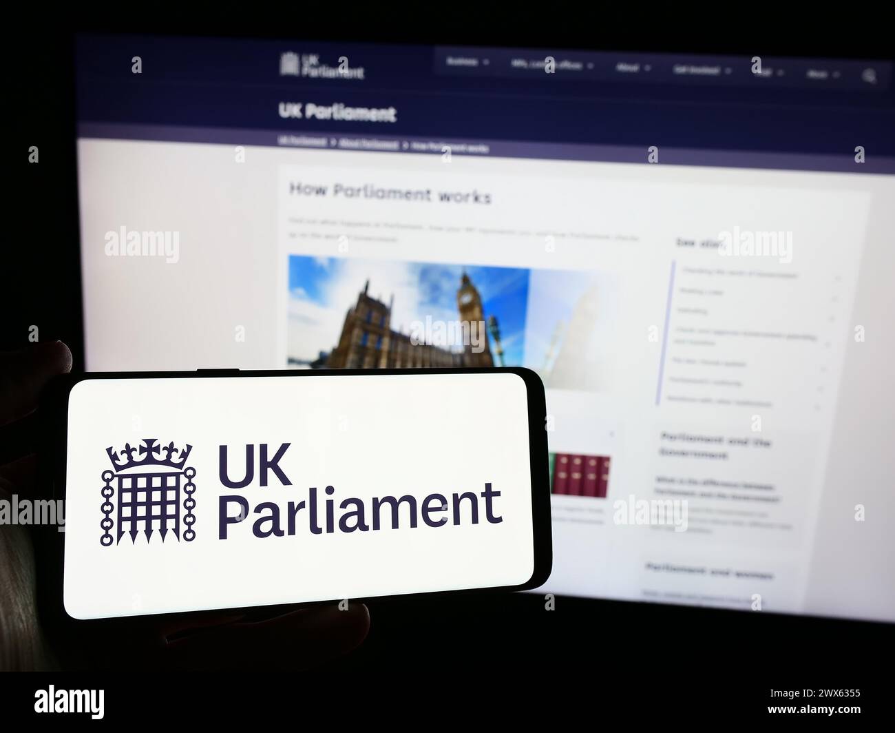 Persona che possiede uno smartphone con il logo dell'organo legislativo Parlamento del Regno Unito (UK) davanti al sito web. Mettere a fuoco il display del telefono. Foto Stock