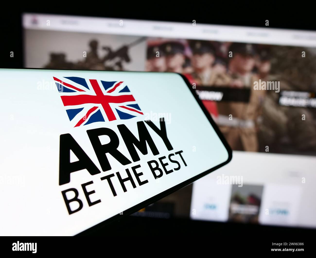 Telefono cellulare con logo della forza di terra britannica British Army davanti al sito web. Messa a fuoco al centro del display del telefono. Foto Stock