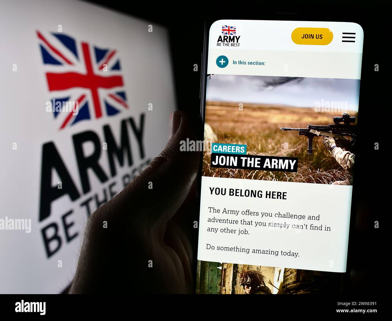 Persona che tiene un cellulare con pagina web della forza di terra britannica British Army davanti al logo. Messa a fuoco al centro del display del telefono. Foto Stock