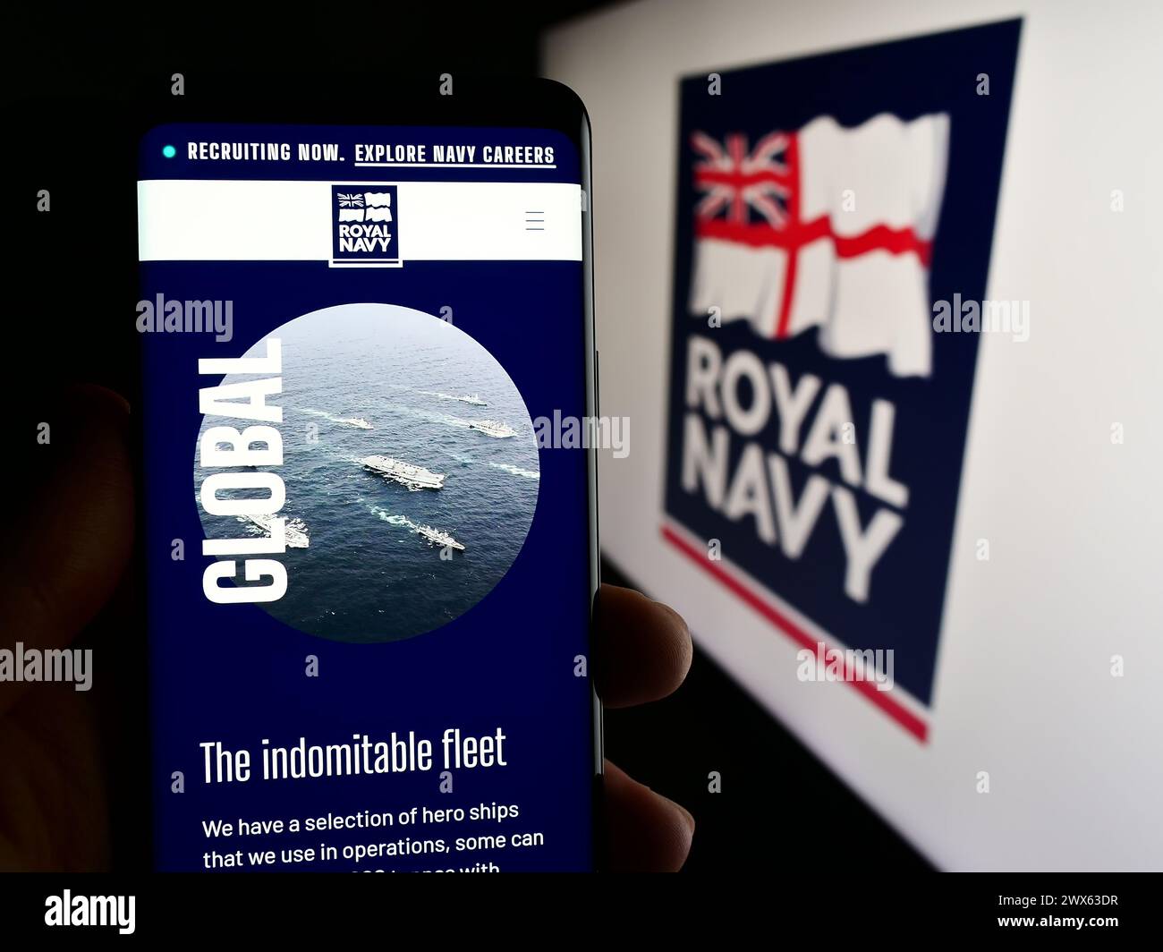 Persona che possiede uno smartphone con pagina Web della guerra navale britannica Royal Navy (RN) davanti al logo. Messa a fuoco al centro del display del telefono. Foto Stock