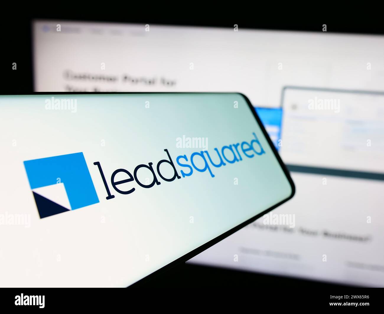 Persona con smartphone con logo della società indiana di piattaforme CRM LeadSquared davanti al sito Web. Mettere a fuoco la parte centrale sinistra del display del telefono. Foto Stock