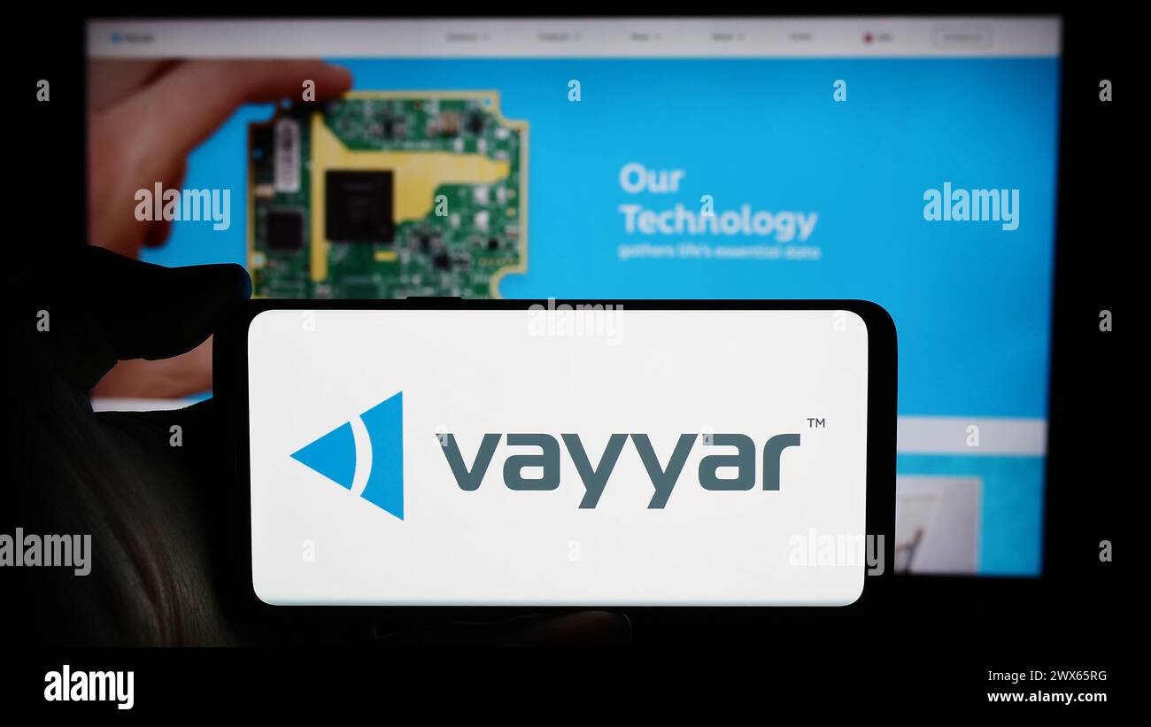 Persona che detiene un cellulare con il logo della società israeliana di semiconduttori Vayyar Imaging Ltd. Di fronte alla pagina Web aziendale. Mettere a fuoco il display del telefono. Foto Stock