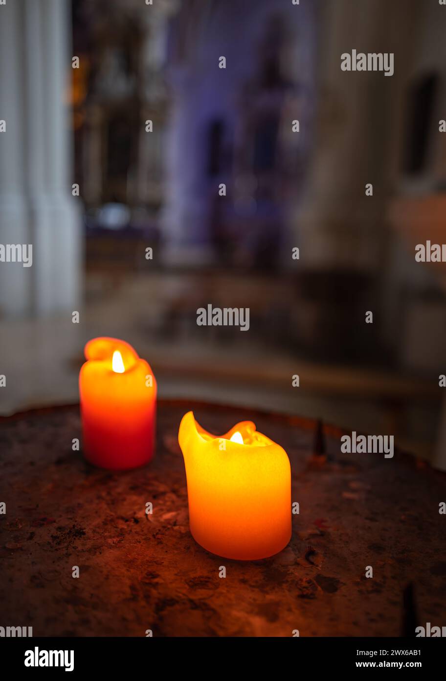 Due candele votive accese in una chiesa con sfondo sfocato Foto Stock