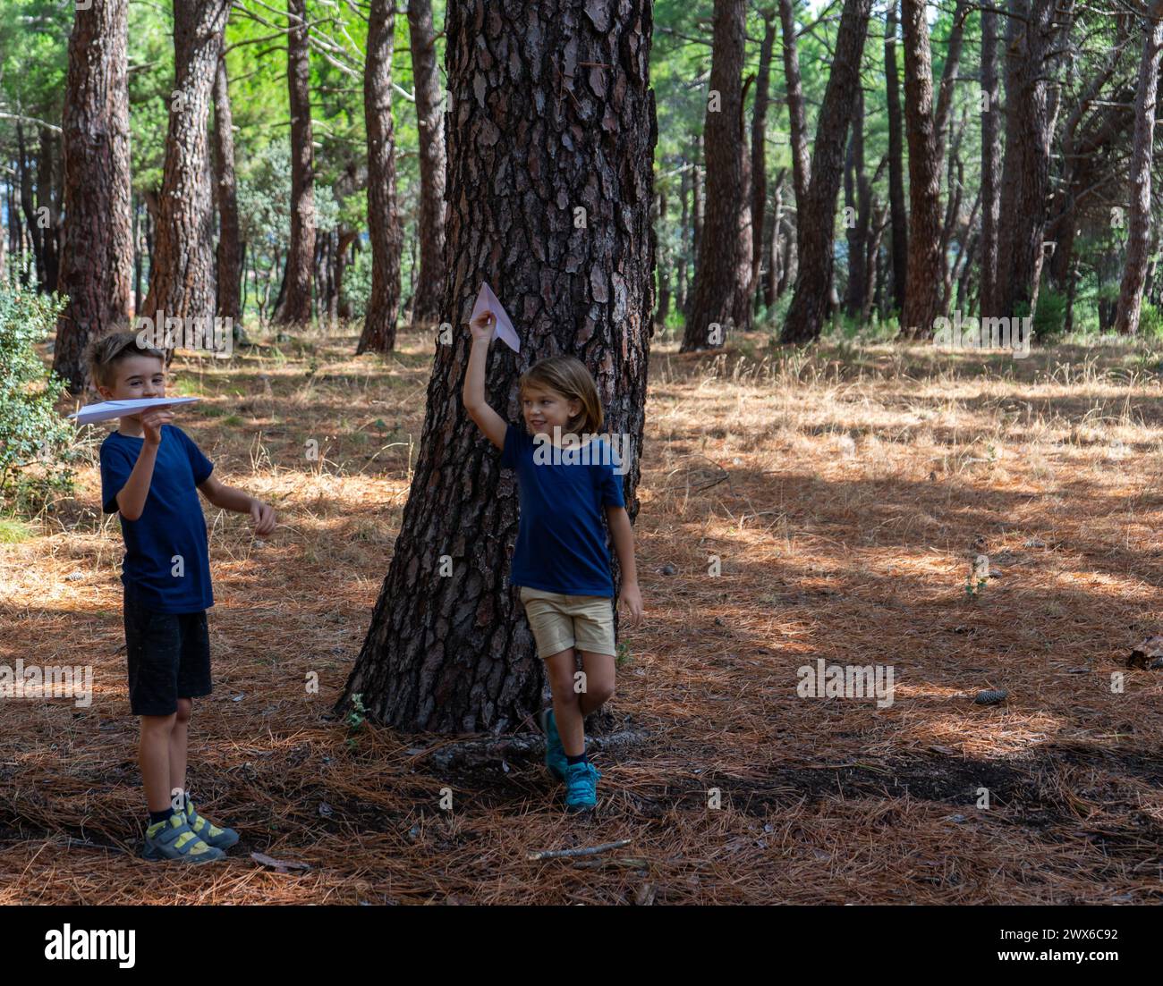 Bambini che giocano con aerei di carta nella foresta Foto Stock