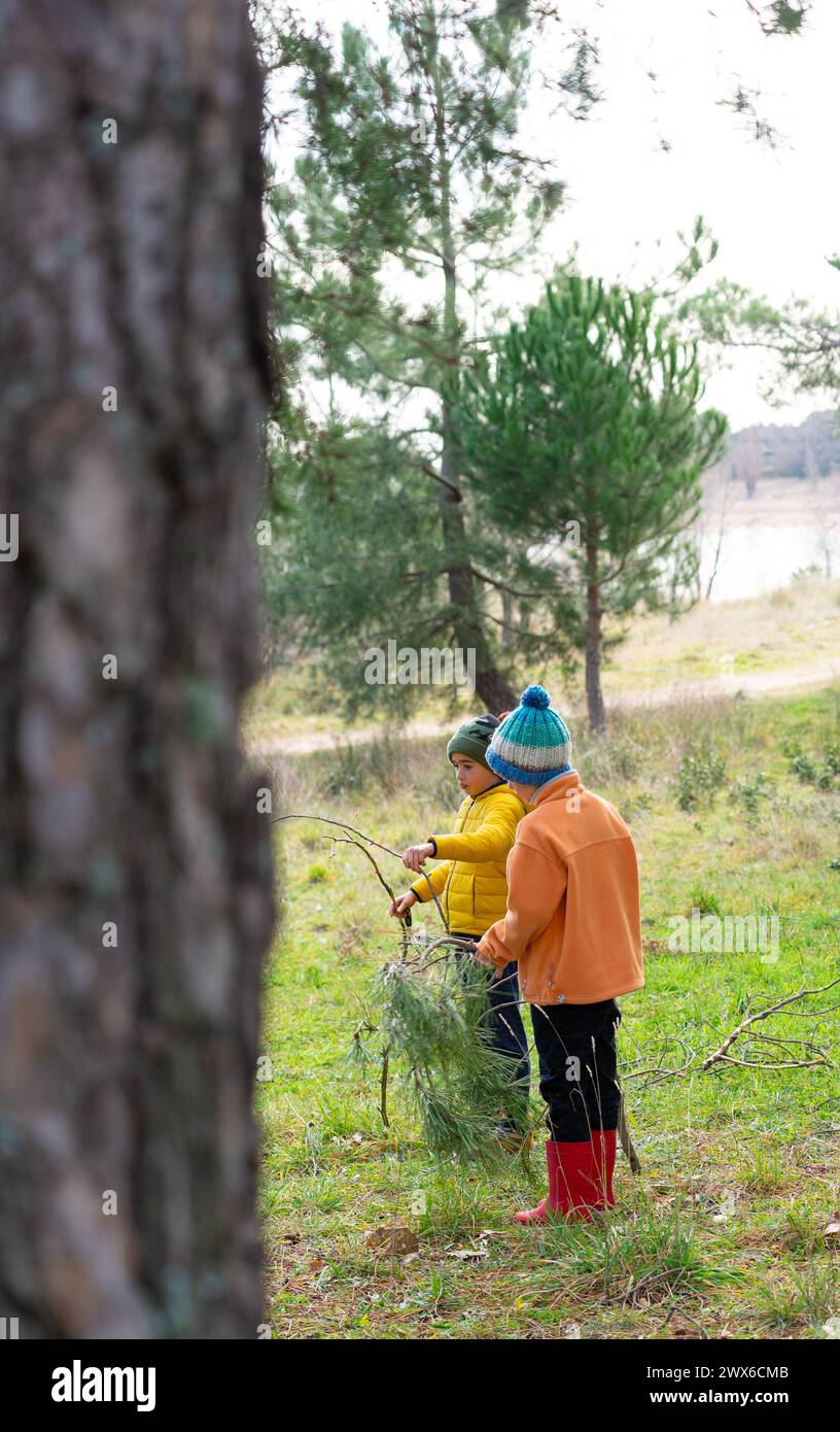 Due bambini che giocano in una foresta con elementi della natura Foto Stock