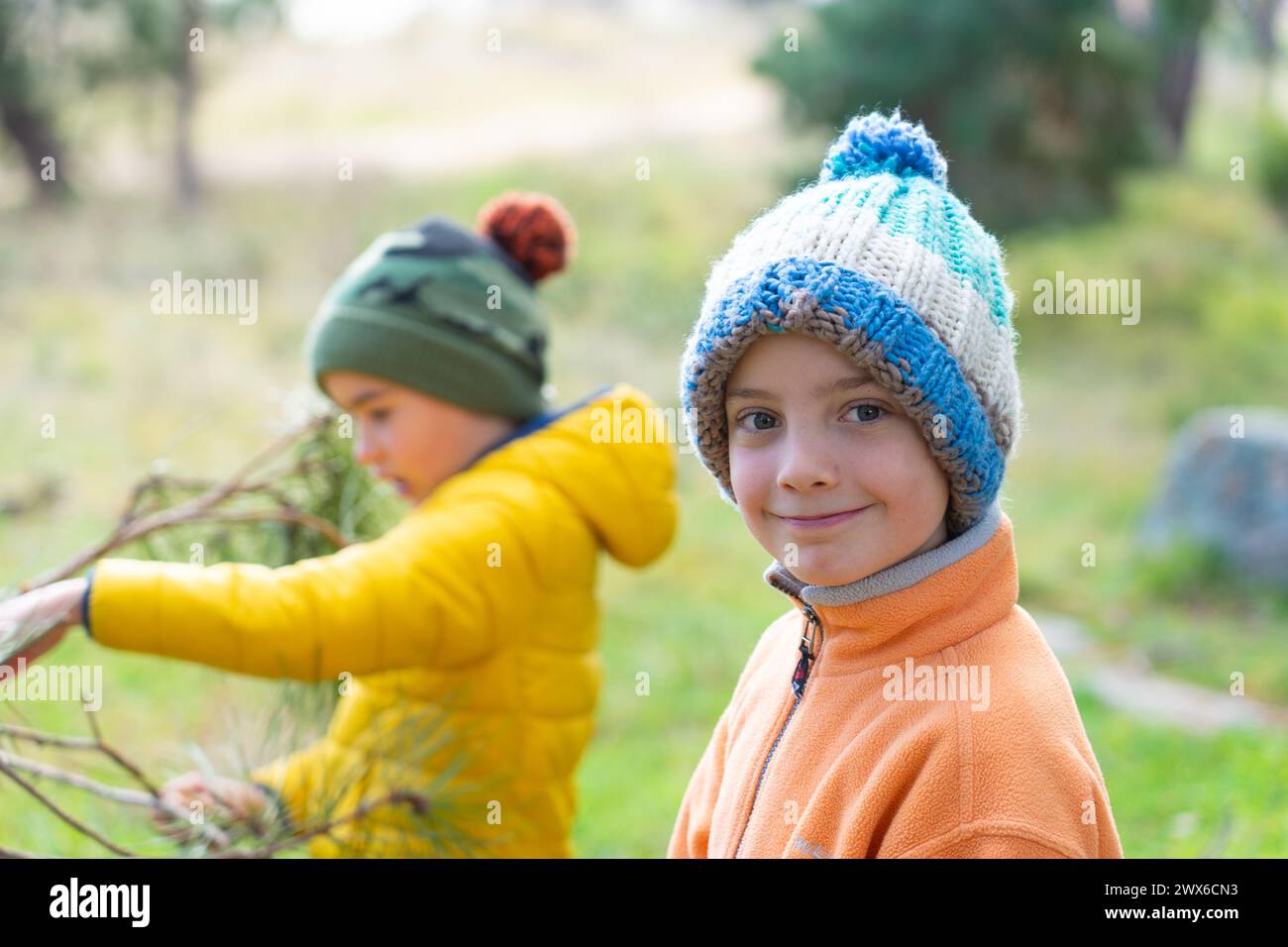 Bambini che giocano in natura, uno che guarda la macchina fotografica sorridendo Foto Stock