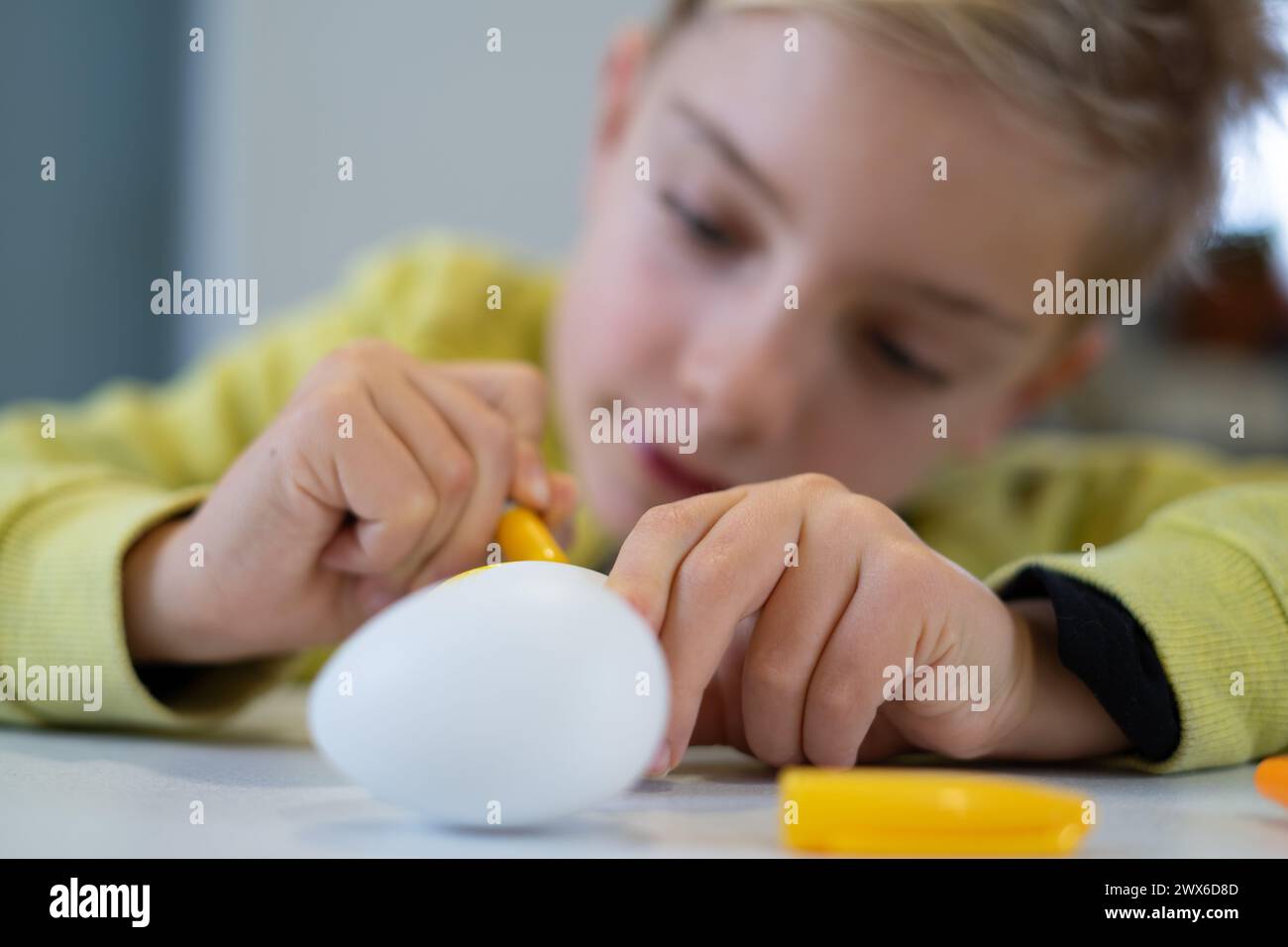 Ragazzo che dipinge un uovo di pasqua a casa Foto Stock