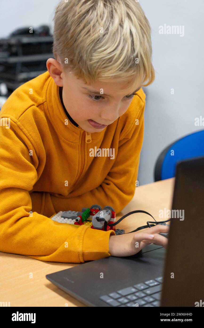 Bambino concentrato in un'officina robotica che guarda il computer Foto Stock