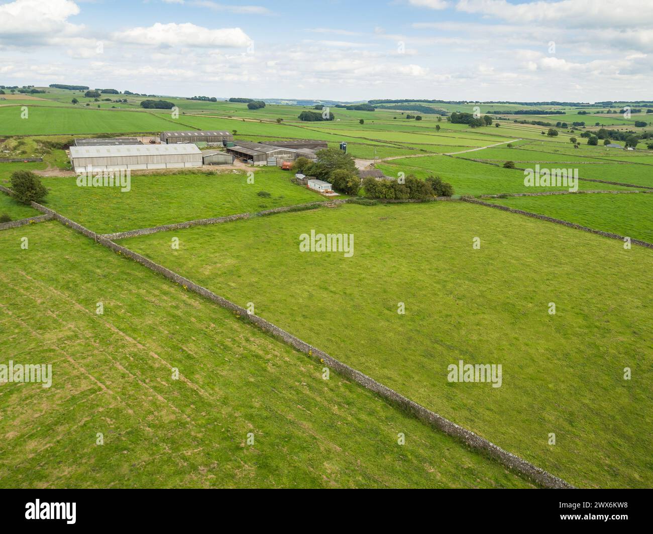 Fotografia dei campi e della campagna del Peak District con muretti a secco e una fattoria in lontananza, Derbyshire, Regno Unito Foto Stock