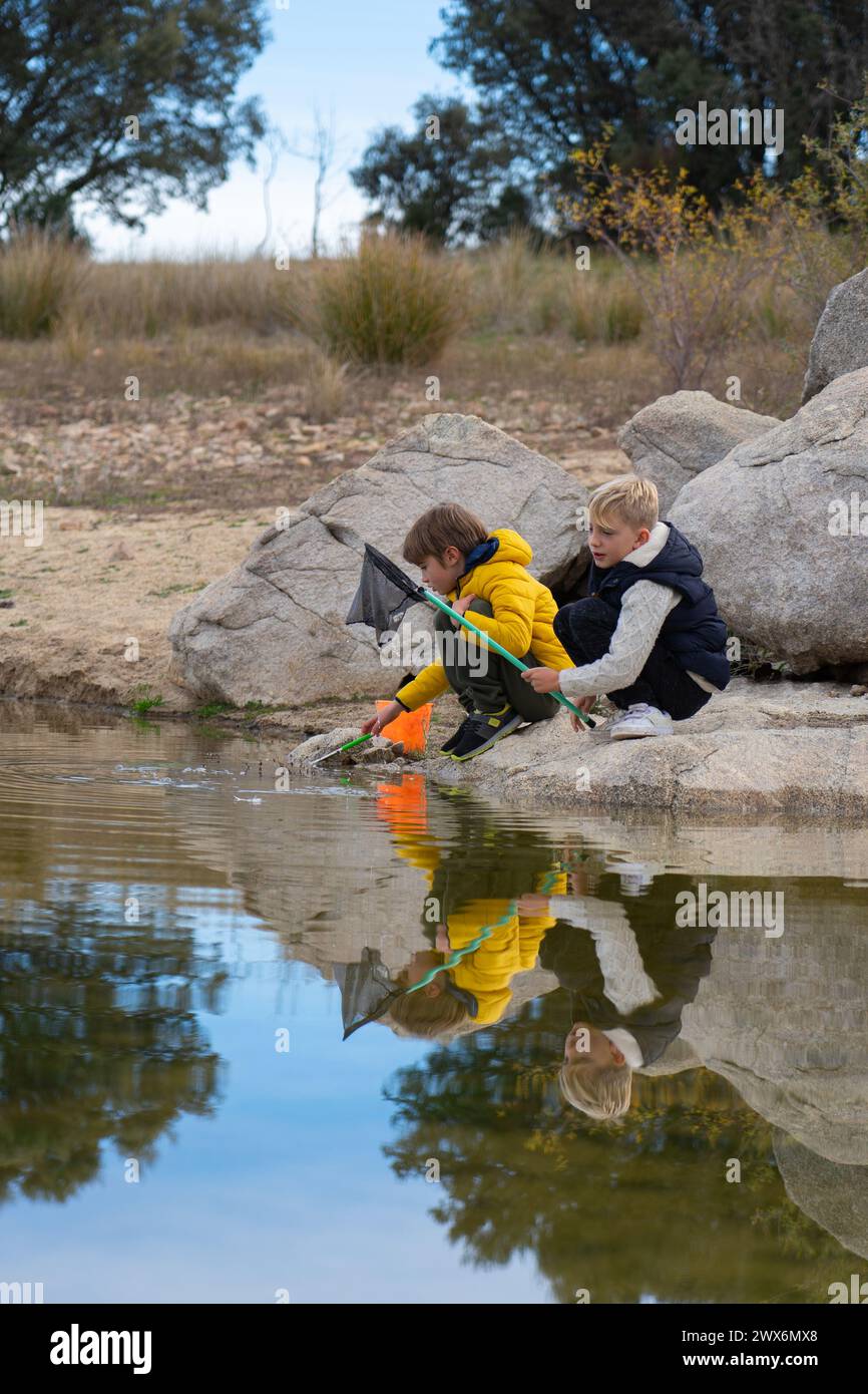 Due bambini che giocano a pesca in un lago Foto Stock