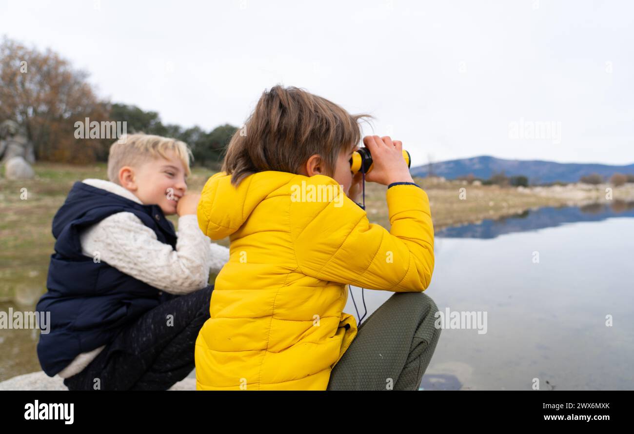 Bambini che giocano con il binocolo in un lago in natura Foto Stock