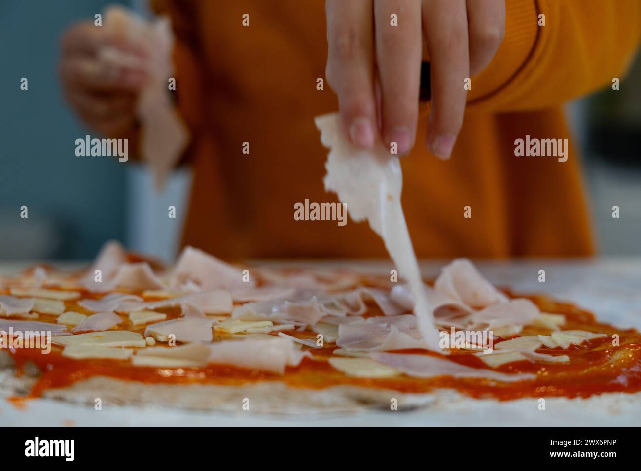 Le mani dei bambini cucinano pizza fatta in casa mettendo gli ingredienti sull'impasto Foto Stock