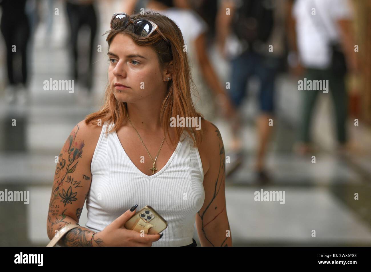 Ragazza italiana con braccio tatuato che cammina in via Ugo Bassi, Bologna, Italia. Foto Stock