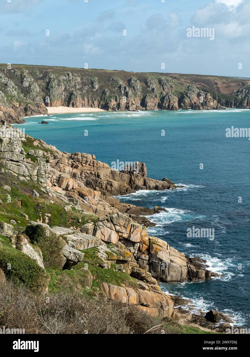 Costa rocciosa della Cornovaglia vicino a Porthcurno con spiaggia Pedn Vounder in lontananza, Cornovaglia, Inghilterra, Regno Unito Foto Stock