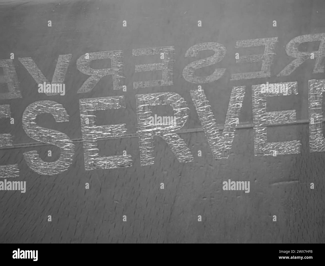 Minimalismo monocromatico. Cartello di plastica riservato, sul tavolo. Bianco e nero, colori. Le parole giocano. Lettere da entrambi i lati. Servire e riservare. Foto Stock