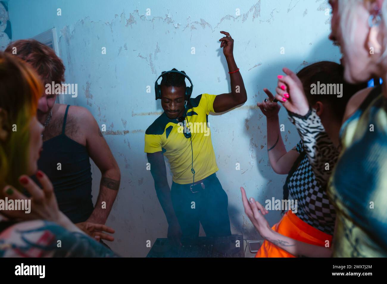 DJ non binario che suona musica e discoteca con gli amici nell'appartamento Foto Stock