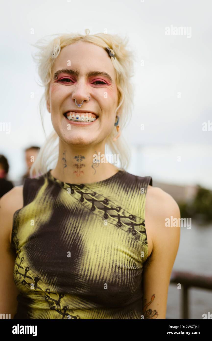 Ritratto di una persona allegra non binaria con capelli biondi Foto Stock