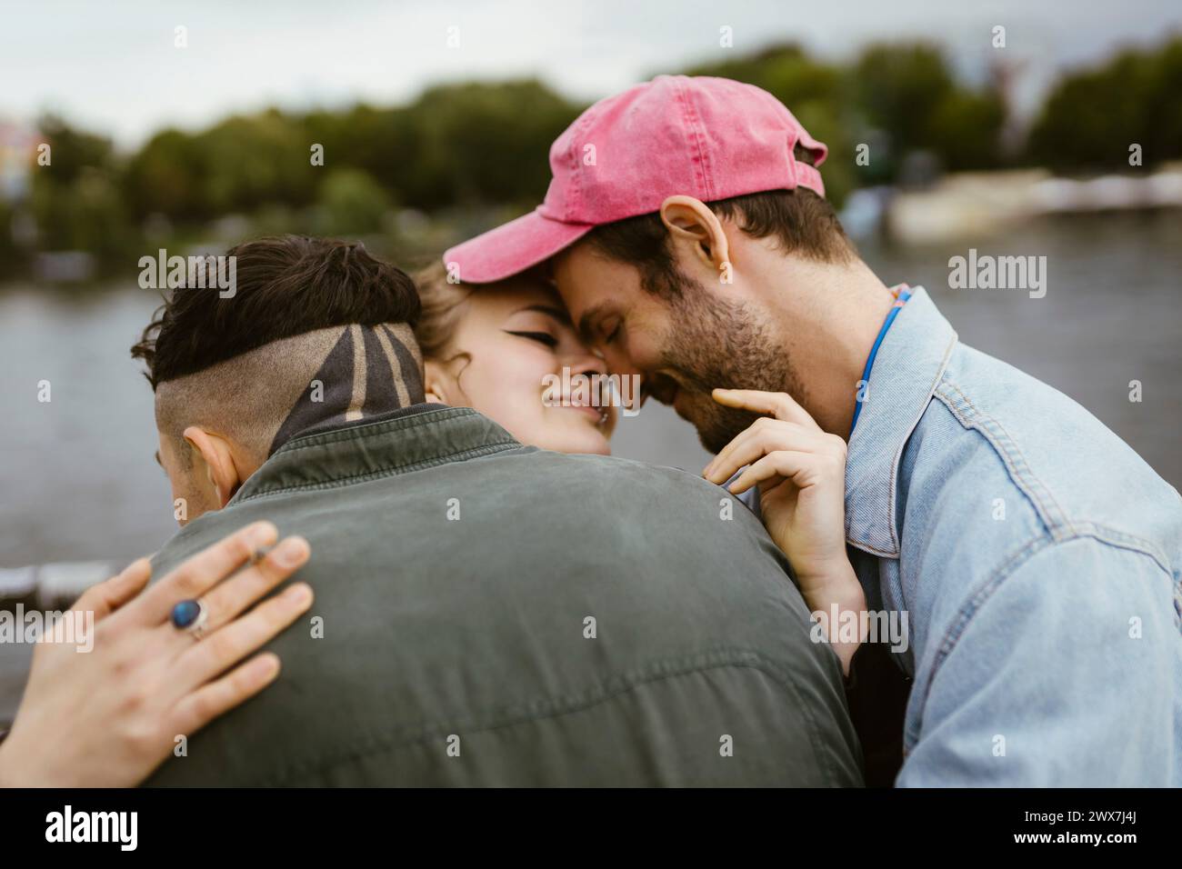 Sorridente persona non binaria che abbraccia gli amici Foto Stock