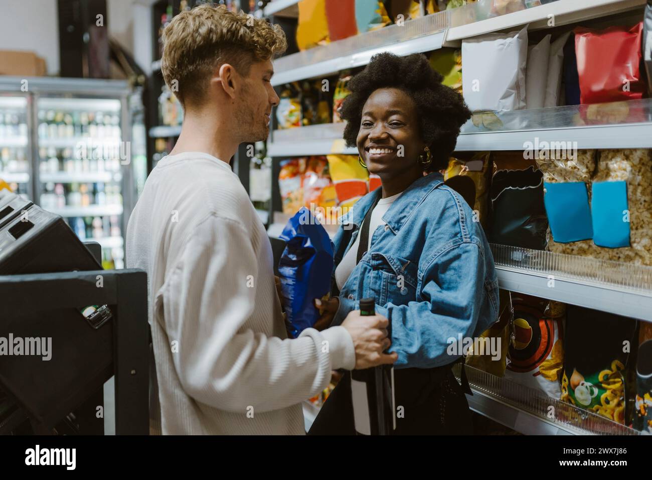 Una giovane donna sorridente che fa shopping con il fidanzato mentre si trova al Aisle in un supermercato Foto Stock