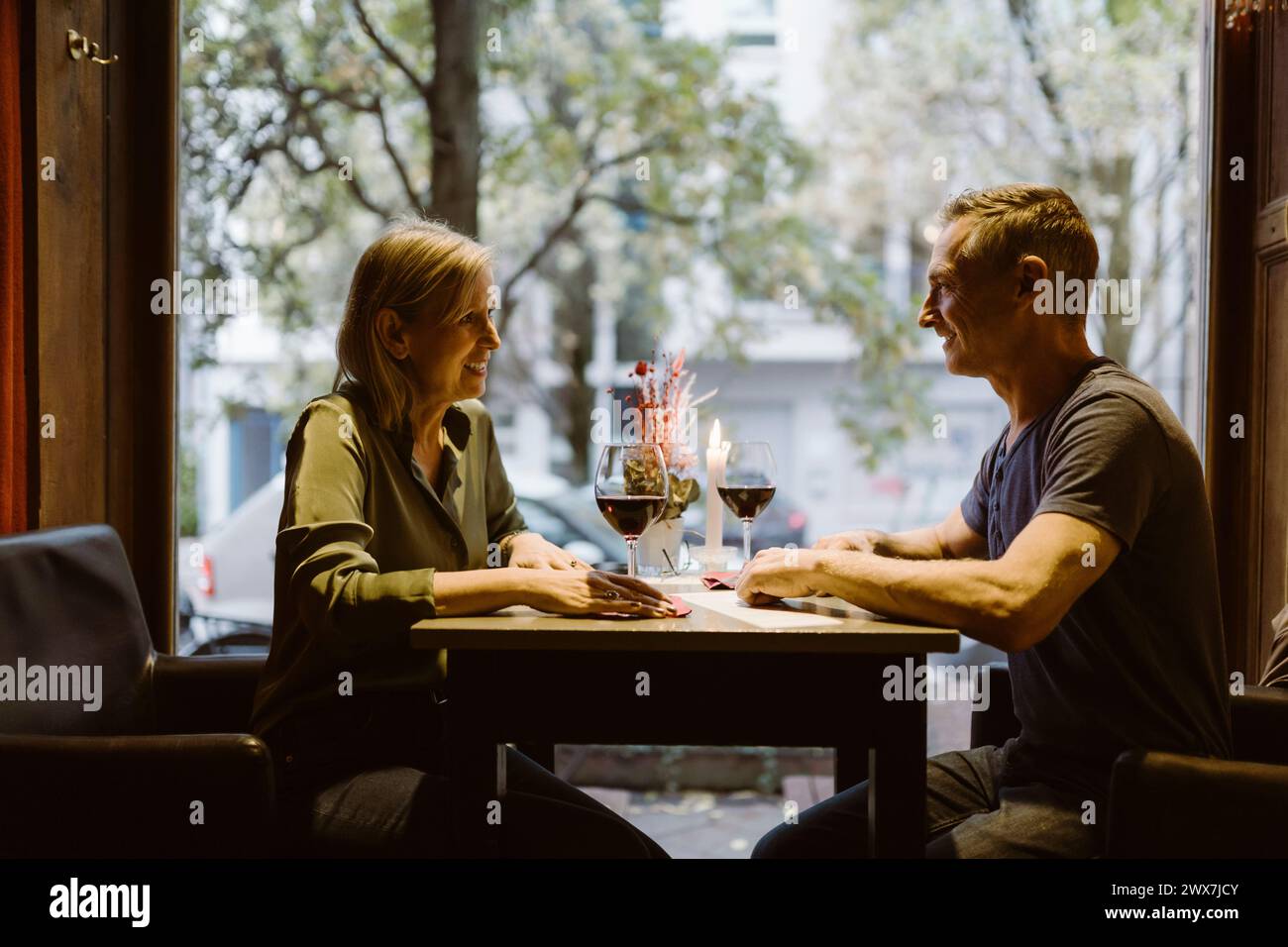 Una coppia matura sorridente si guarda mentre beve del vino al bar Foto Stock