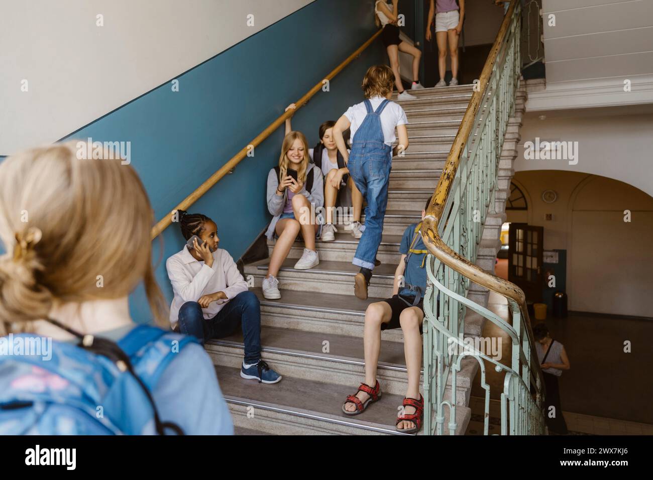 Studenti di sesso maschile e femminile che si divertono sui gradini a scuola Foto Stock