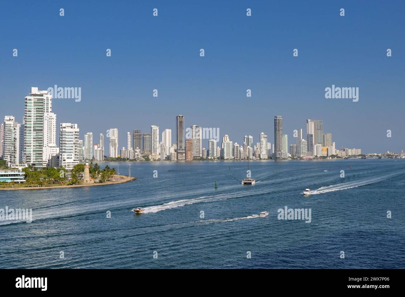 Cartagena, Colombia - 24 gennaio 2024: Barche che passano davanti al Naval Club e al faro all'ingresso del porto della città Foto Stock